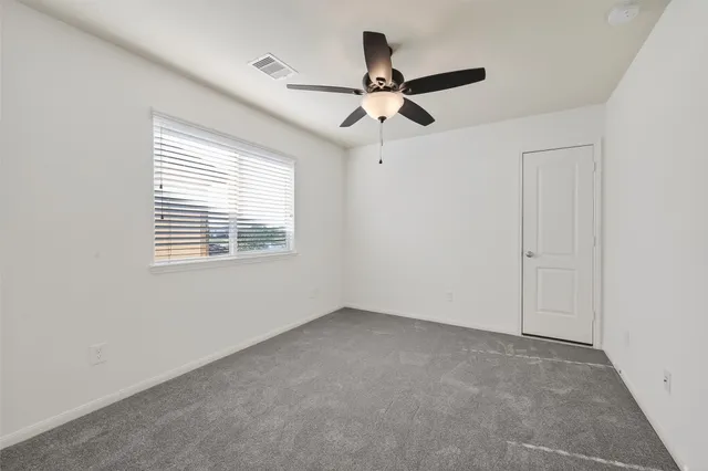 an empty room with a window and a fan