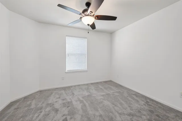 an empty room with a window and a fan