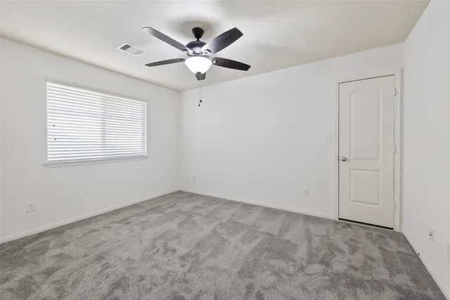 an empty room with a window and a fan