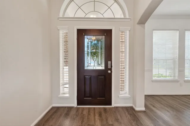 an empty room with wooden floor closet and windows