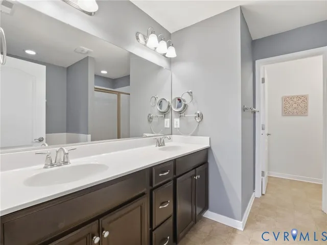 a spacious bathroom with a double vanity sink a mirror and a bathtub