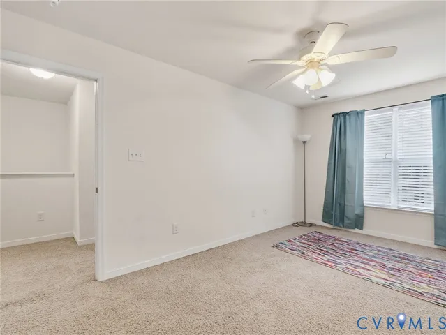 an empty room with a chandelier fan and windows