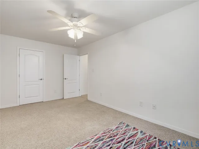 an empty room with a chandelier fan and windows