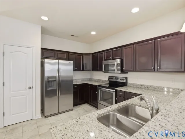 a kitchen with stainless steel appliances kitchen island granite countertop a refrigerator a stove a dining table and chairs with wooden floor