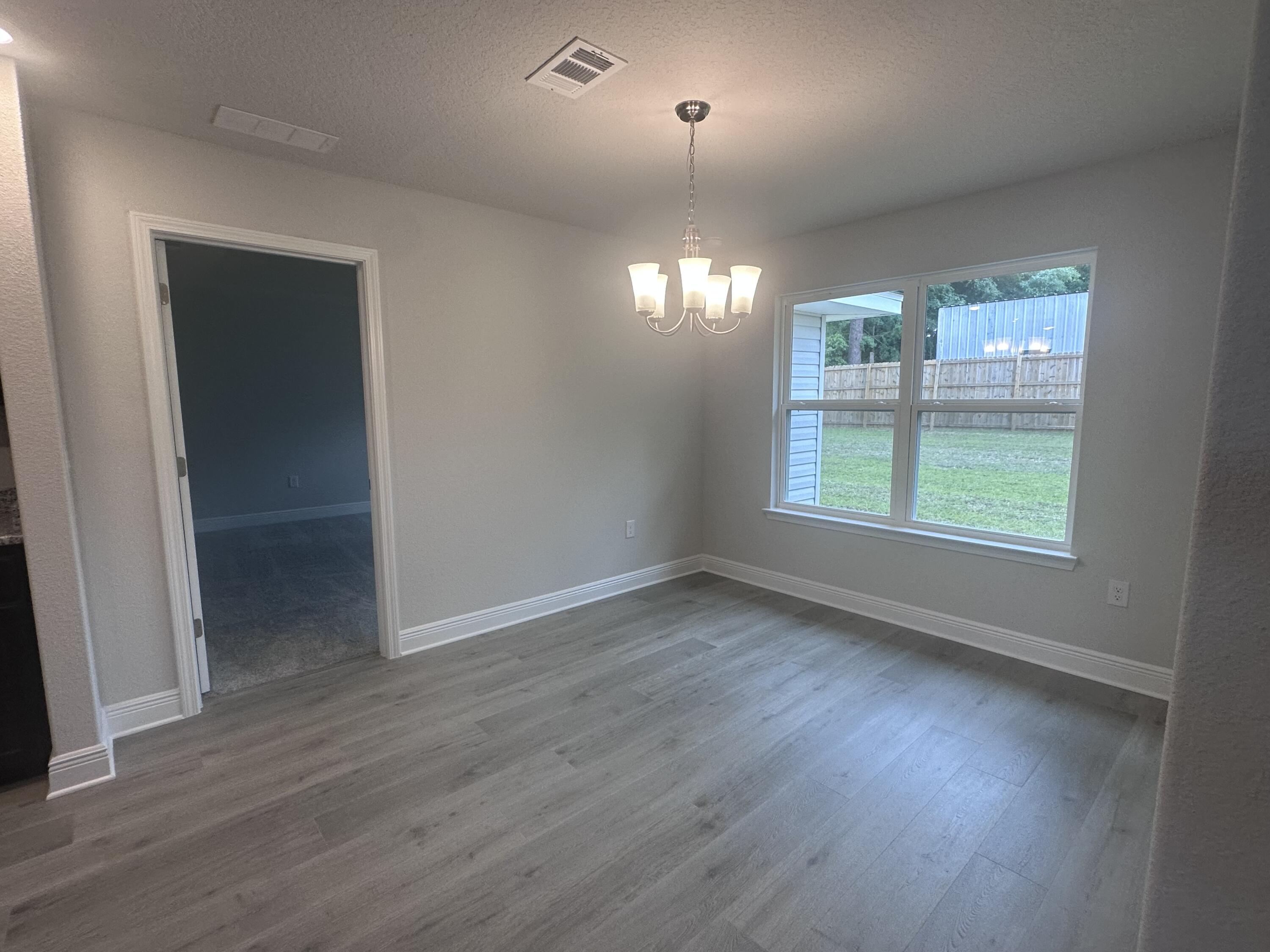 6115 Buckshot Drive Crestview, FL 32539 - Photo 12 of 29 an empty room with wooden floor and windows