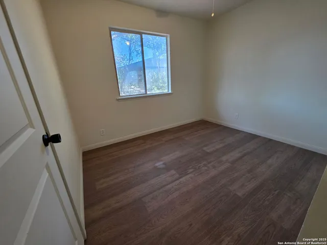a view of an empty room with wooden floor and a window