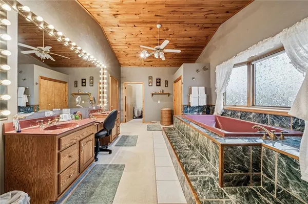 a spacious bedroom with a bed and a flat tv screen on dresser