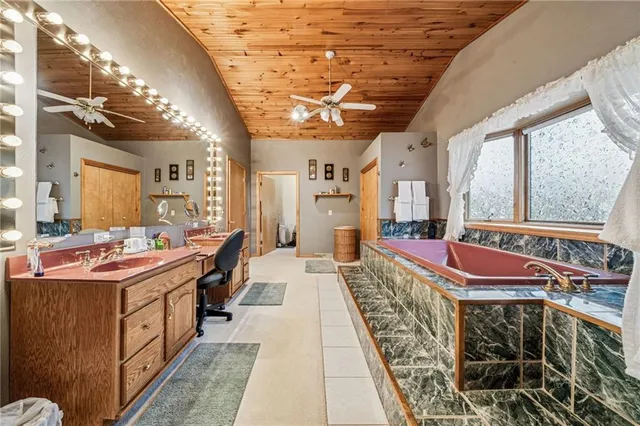 a spacious bedroom with a bed and a flat tv screen on dresser