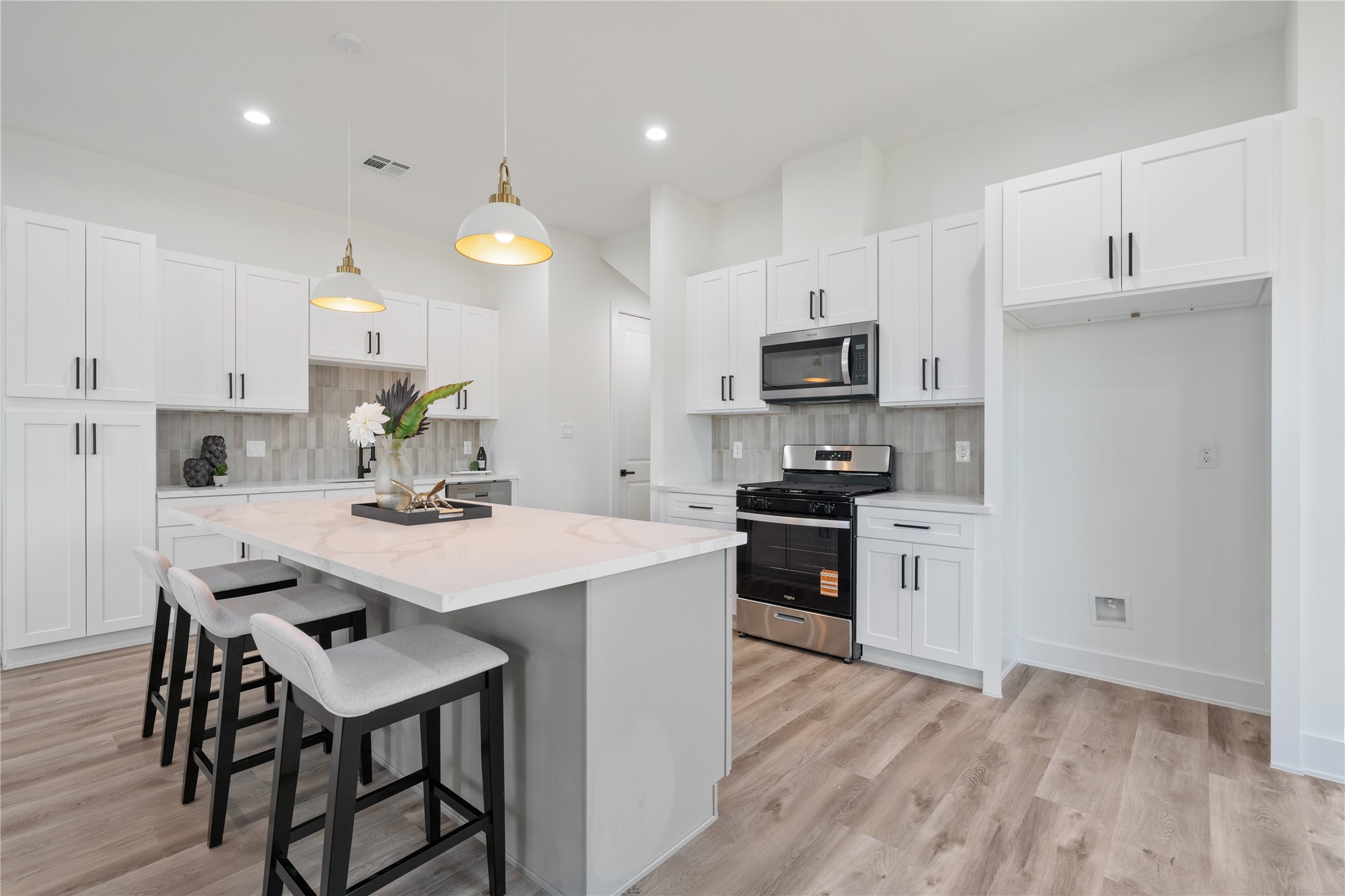 9003 Comal Street Houston, TX 77051 - Photo 4 of 36 The kitchen features elegant white cabinetry paired with a massive quartz countertops and a gray accent island, combining style and functionality. It’s a bright, inviting space perfect for cooking, entertaining, and gathering with family. The thoughtful design makes both daily life and special occasions effortless.
