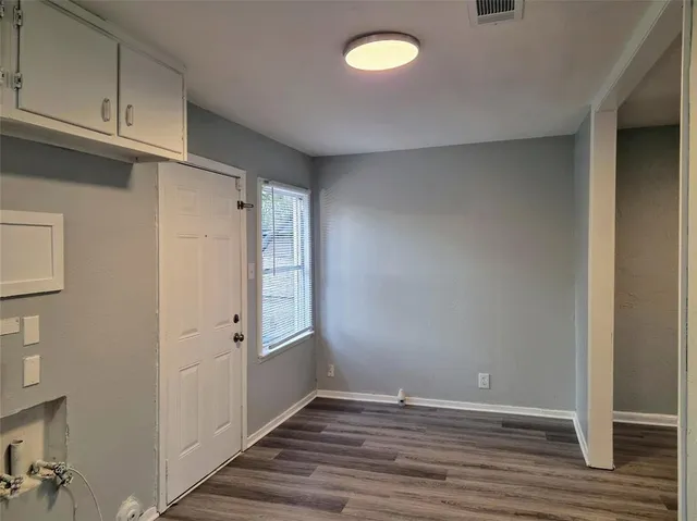 a view of an empty room with wooden floor and entryway