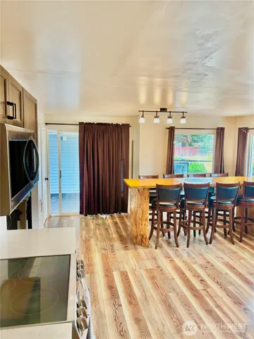 a living room with stainless steel appliances furniture a fireplace and a open kitchen view