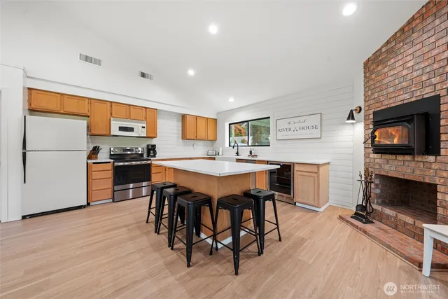 a open kitchen with stainless steel appliances granite countertop a stove a refrigerator a sink a dining table and chairs with wooden floor