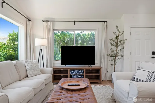 a living room with furniture a flat screen tv and a large window