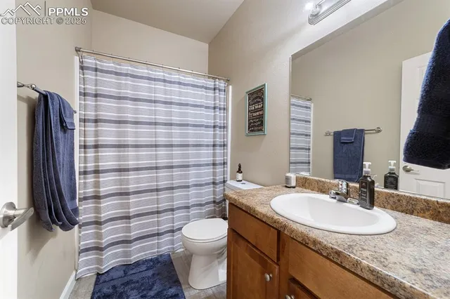 a bathroom with a granite countertop toilet sink and mirror