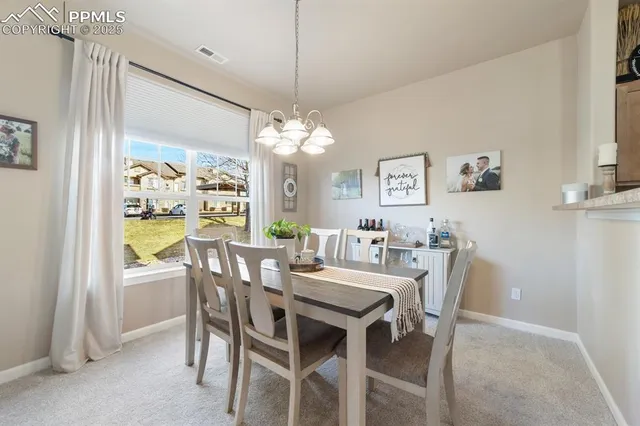 a view of a dining room with furniture a chandelier and a window