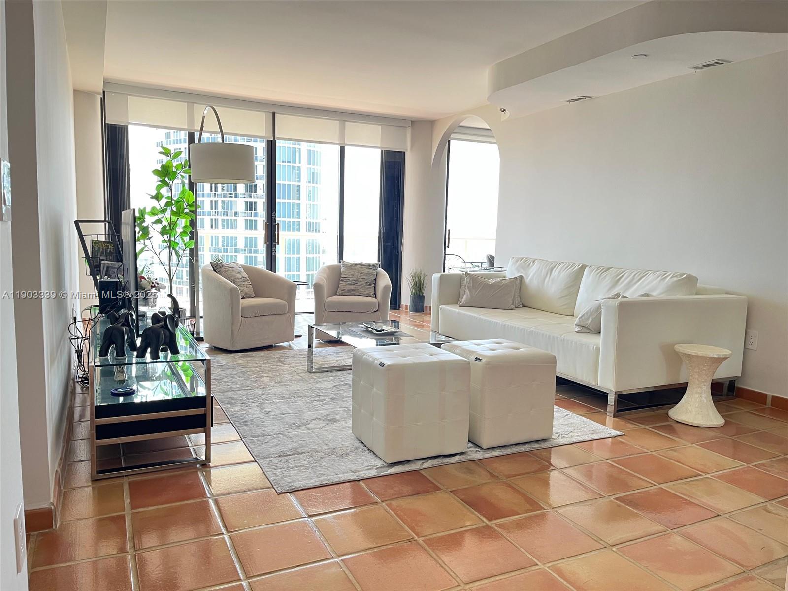 4000 Island Boulevard, Unit 1703 Aventura, FL 33160 - Photo 9 of 29 a living room with couches a coffee table and a table with wooden floor