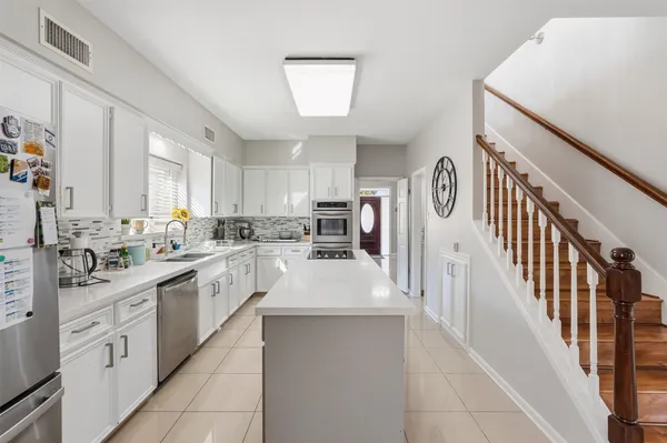 a large white kitchen with lots of counter space cabinets and a sink