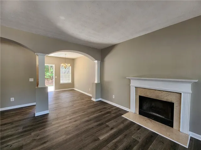 an empty room with wooden floor fireplace and windows