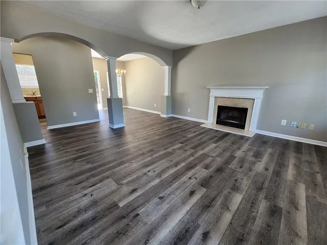 a view of an empty room with wooden floor and a fireplace