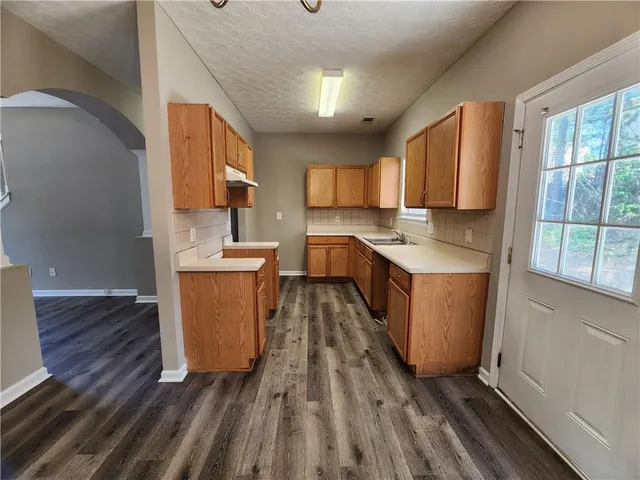 a kitchen with granite countertop a sink stove and wooden cabinets