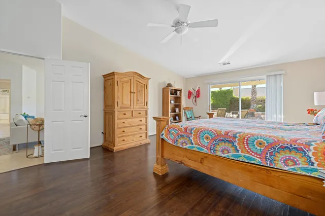 a spacious bedroom with a bed a dresser and wooden floor