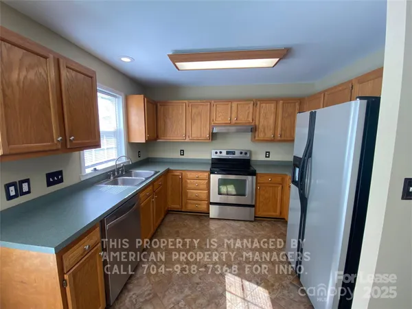 a kitchen with stainless steel appliances granite countertop a refrigerator sink and stove