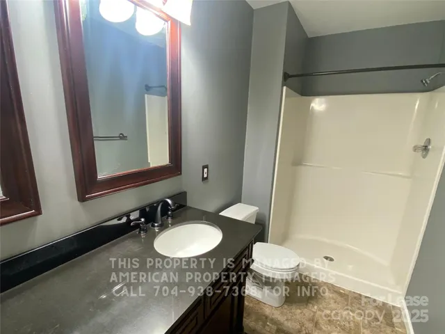 a bathroom with a granite countertop sink toilet and shower