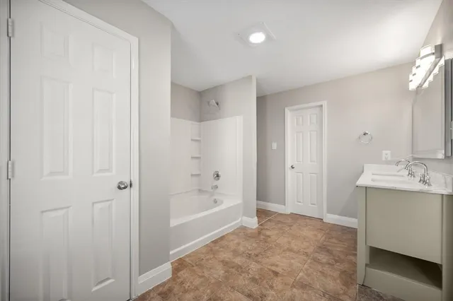 a bathroom with a tub sink and mirror
