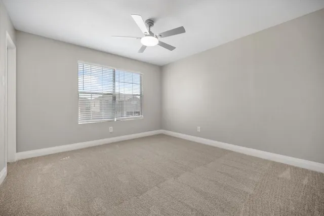 an empty room with windows and ceiling fan