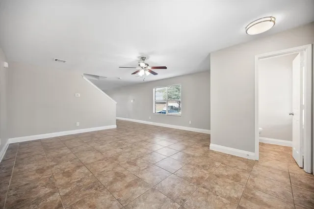 an empty room with windows and chandelier fan