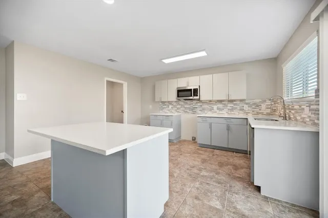 a kitchen with a sink a stove a refrigerator a center island and cabinets