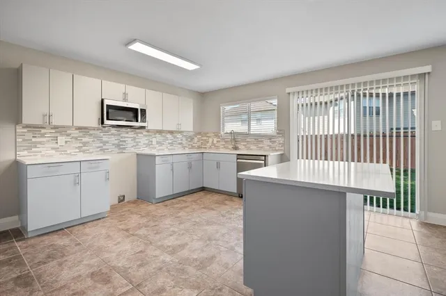 a kitchen with stainless steel appliances granite countertop a stove top oven a sink dishwasher and a refrigerator