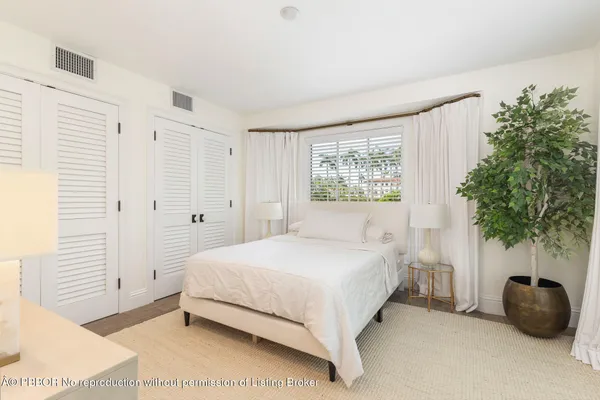 a bedroom with a bed a plant and a window