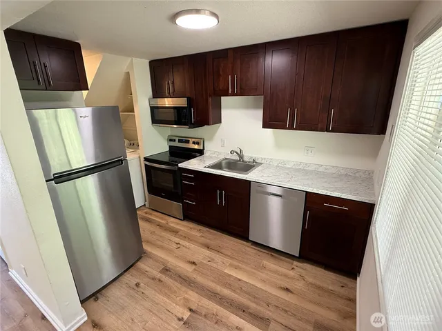 a kitchen with stainless steel appliances granite countertop a refrigerator a stove a sink and a microwave