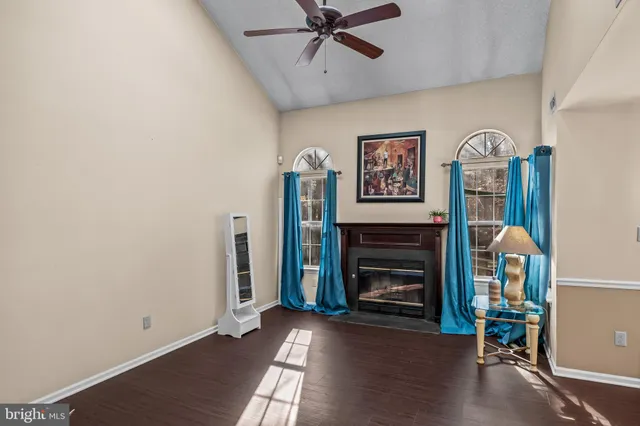 a view of an empty room with wooden floor fireplace and a window