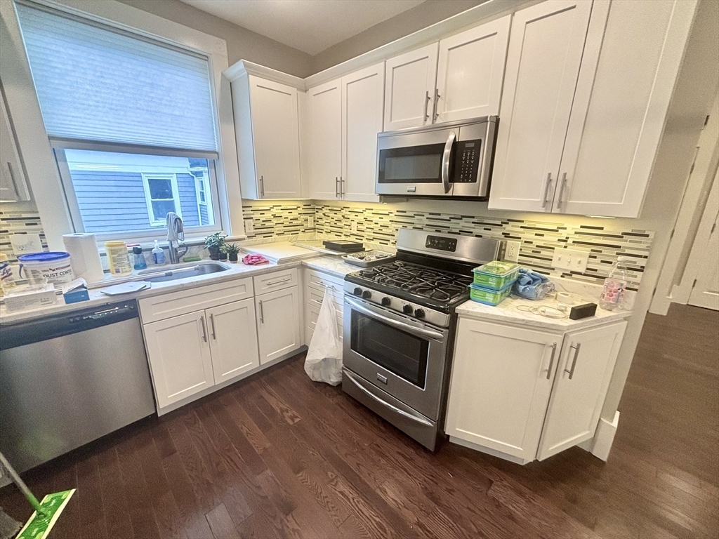 48 Magazine Street, Unit 3 Cambridge, MA 02139 - Photo 6 of 15 a white kitchen with wooden floor and stainless steel appliances