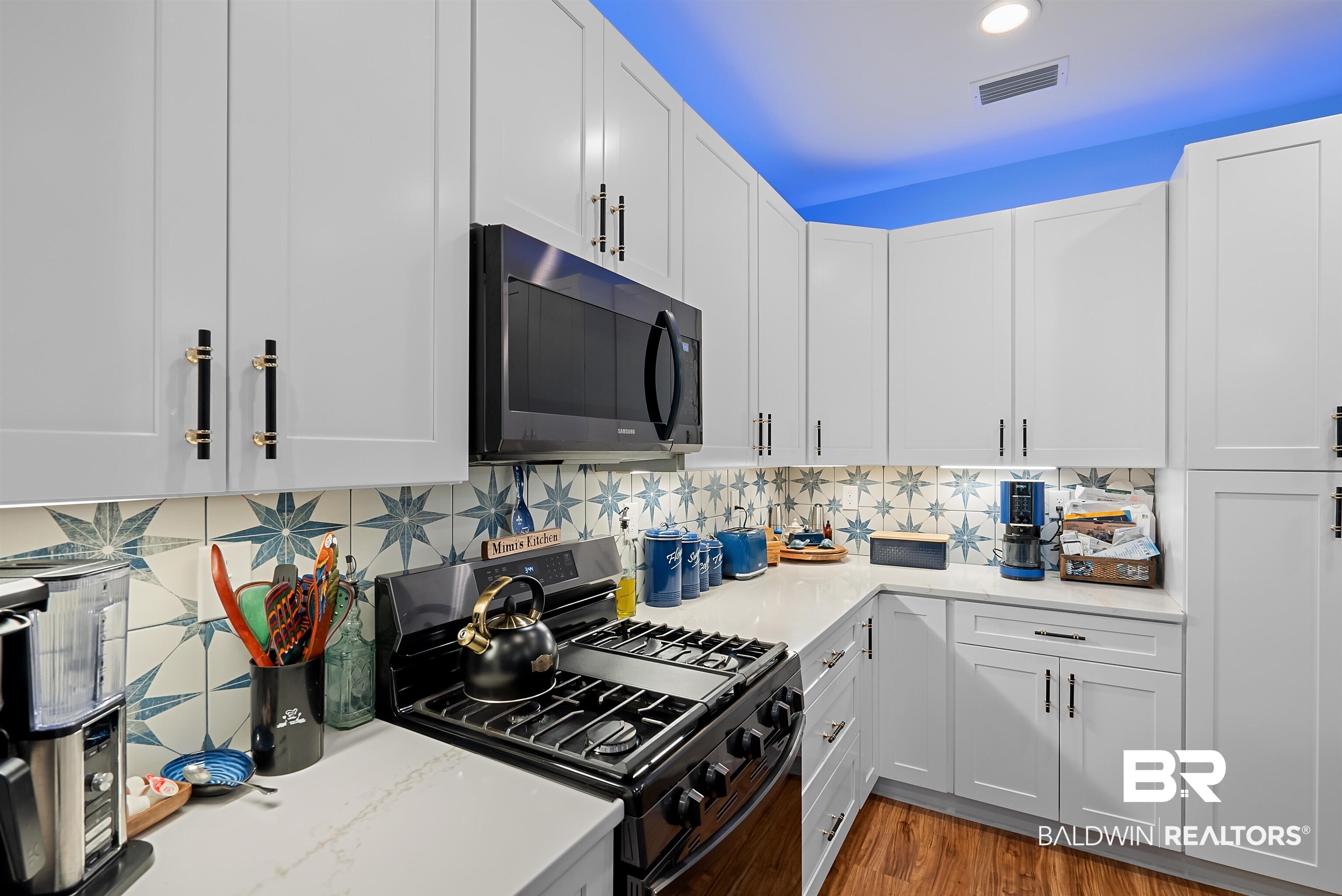 7266 Franklin Road Foley, AL 36535 - Photo 14 of 64 Modern kitchen featuring white shaker cabinetry, patterned tile backsplash, under-cabinet lighting, a built-in microwave, and wood-finish flooring