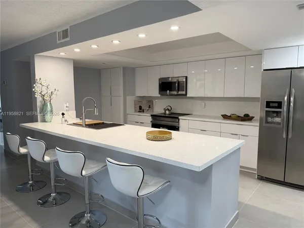 a kitchen with a sink a microwave a refrigerator and chairs
