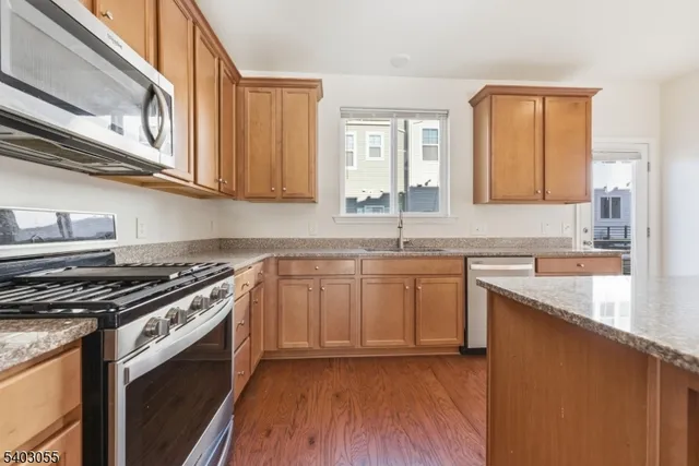 a kitchen with granite countertop a sink a stove cabinets and wooden floor