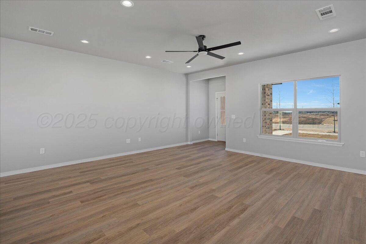 4206 Beacon Road Amarillo, TX 79118 - Photo 5 of 23 an empty room with wooden floor ceiling fan and windows