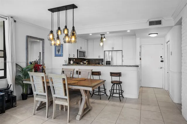 a kitchen with a dining table chairs cabinets and stainless steel appliances