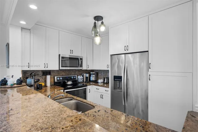 a kitchen with kitchen island granite countertop a refrigerator a sink a stove a microwave and island