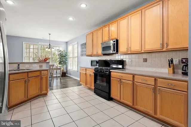 a large kitchen with stainless steel appliances granite countertop a stove a sink and a microwave