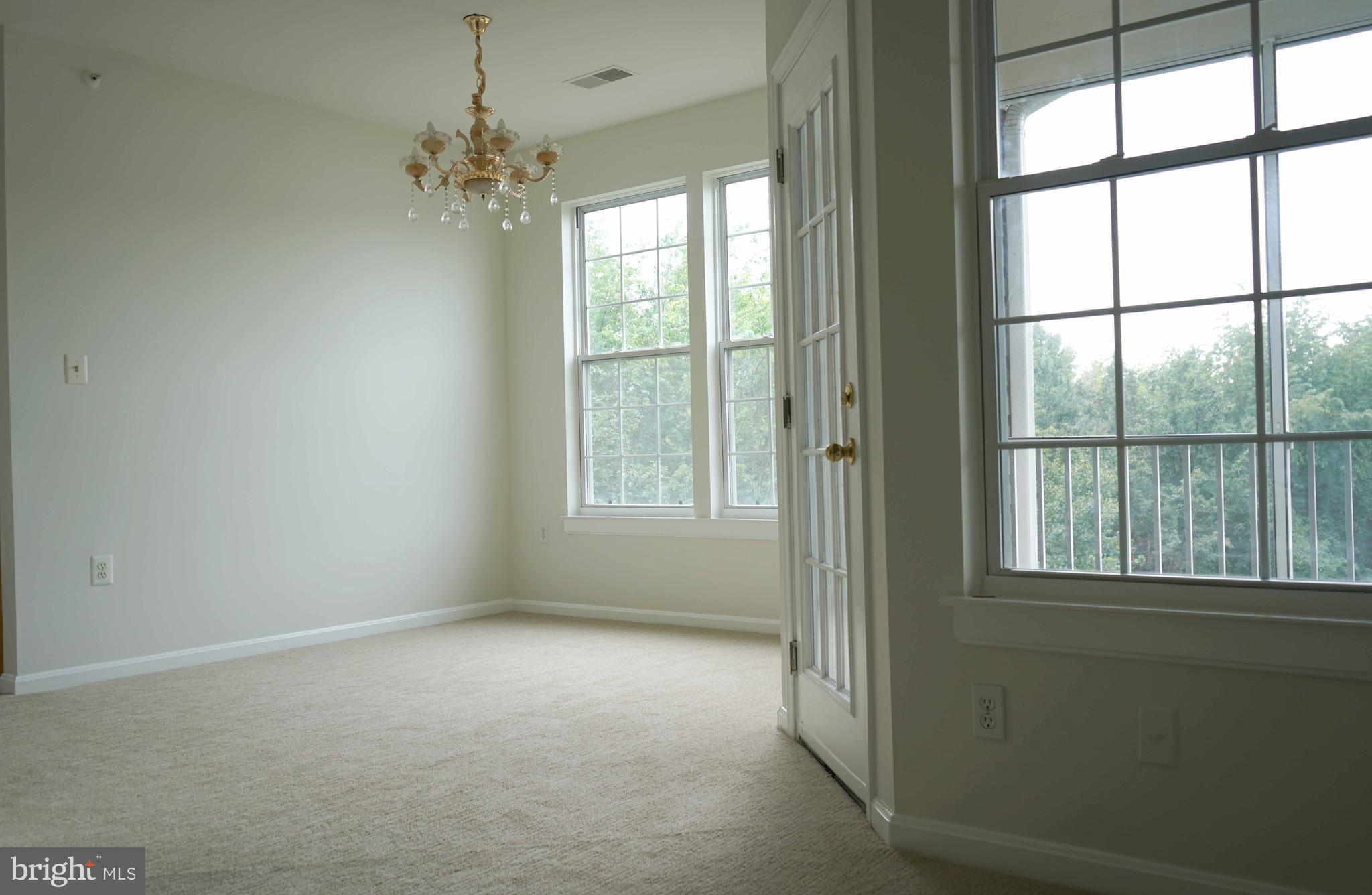 12004 Amber Ridge Circle, Unit B303 Germantown, MD 20876 - Photo 4 of 25 an empty room with windows and chandelier
