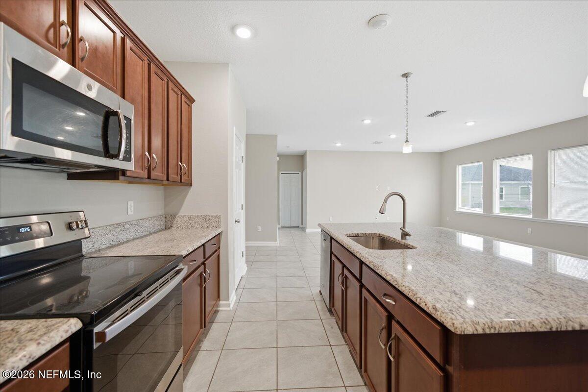 12032 Bridgehampton Road Jacksonville, FL 32218 - Photo 23 of 52 a kitchen with stainless steel appliances granite countertop a sink stove and microwave