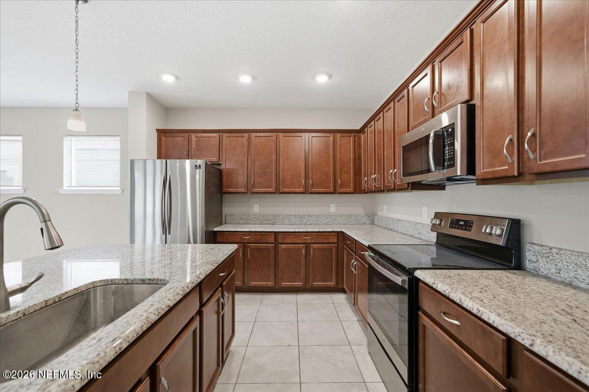 12032 Bridgehampton Road Jacksonville, FL 32218 - Photo 24 of 52 a kitchen with stainless steel appliances granite countertop a sink stove and refrigerator