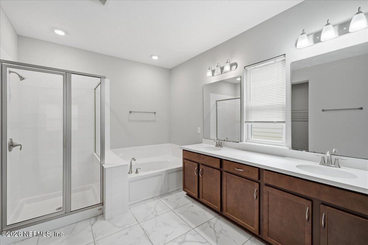 12032 Bridgehampton Road Jacksonville, FL 32218 - Photo 28 of 52 a bathroom with a double vanity sink a large mirror and a bathtub