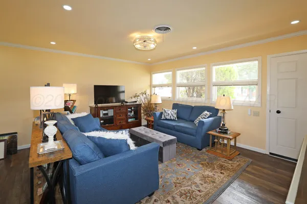 a living room with furniture a flat screen tv and kitchen view
