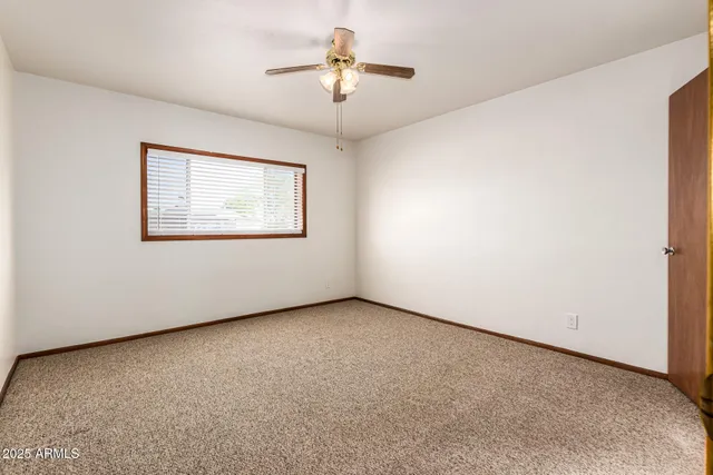 an empty room with a ceiling fan and a window
