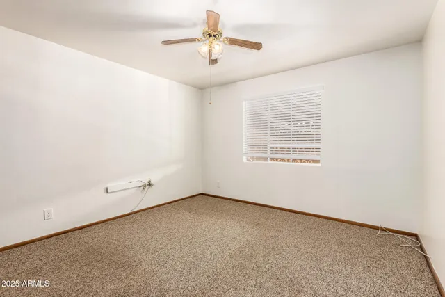 an empty room with chandelier fan and windows